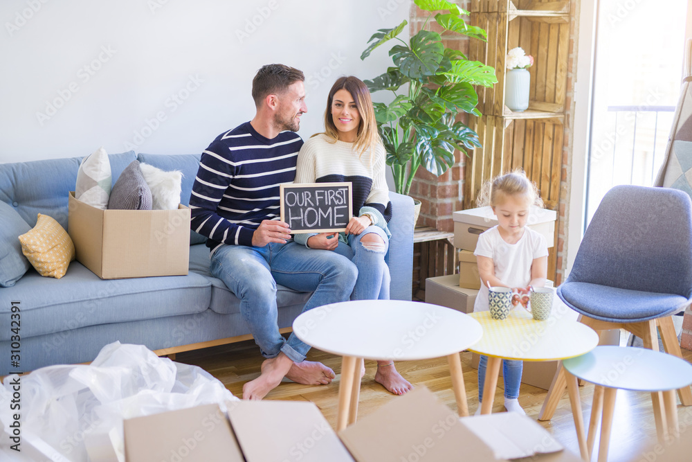 Beautiful famiily with kid sitting on the sofa holding blackboard at new home around cardboard boxes Beautiful famiily with kid sitting on the sofa holding blackboard at new home around cardboard boxes