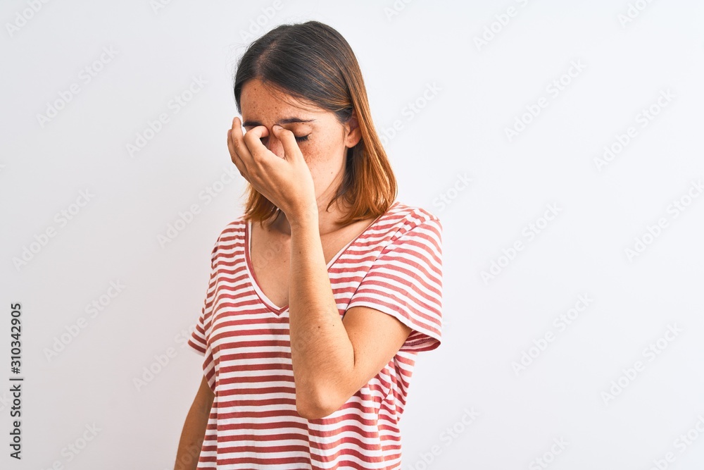 Beautiful redhead woman wearing casual striped red t-shirt over isolated background tired rubbing nose and eyes feeling fatigue and headache. Stress and frustration concept. Beautiful redhead woman wearing casual striped red t-shirt over isolated background tired rubbing nose and eyes feeling fatigue and headache. Stress and frustration concept.