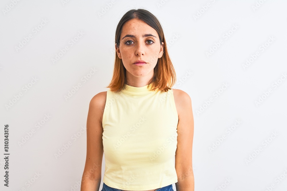 Beautiful redhead woman wearing yellow summer t-shirt over isolated background with serious expression on face. Simple and natural looking at the camera. Beautiful redhead woman wearing yellow summer t-shirt over isolated background with serious expression on face. Simple and natural looking at the camera.