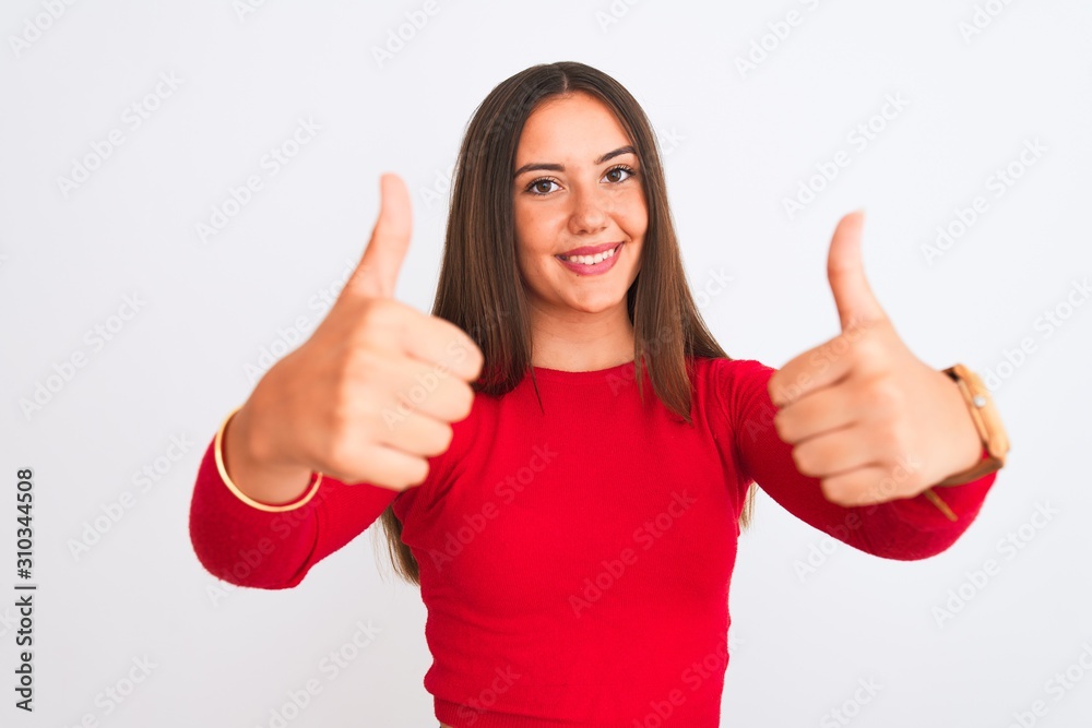 Young beautiful girl wearing red casual t-shirt standing over isolated white background approving doing positive gesture with hand, thumbs up smiling and happy for success. Winner gesture. Young beautiful girl wearing red casual t-shirt standing over isolated white background approving doing positive gesture with hand, thumbs up smiling and happy for success. Winner gesture.