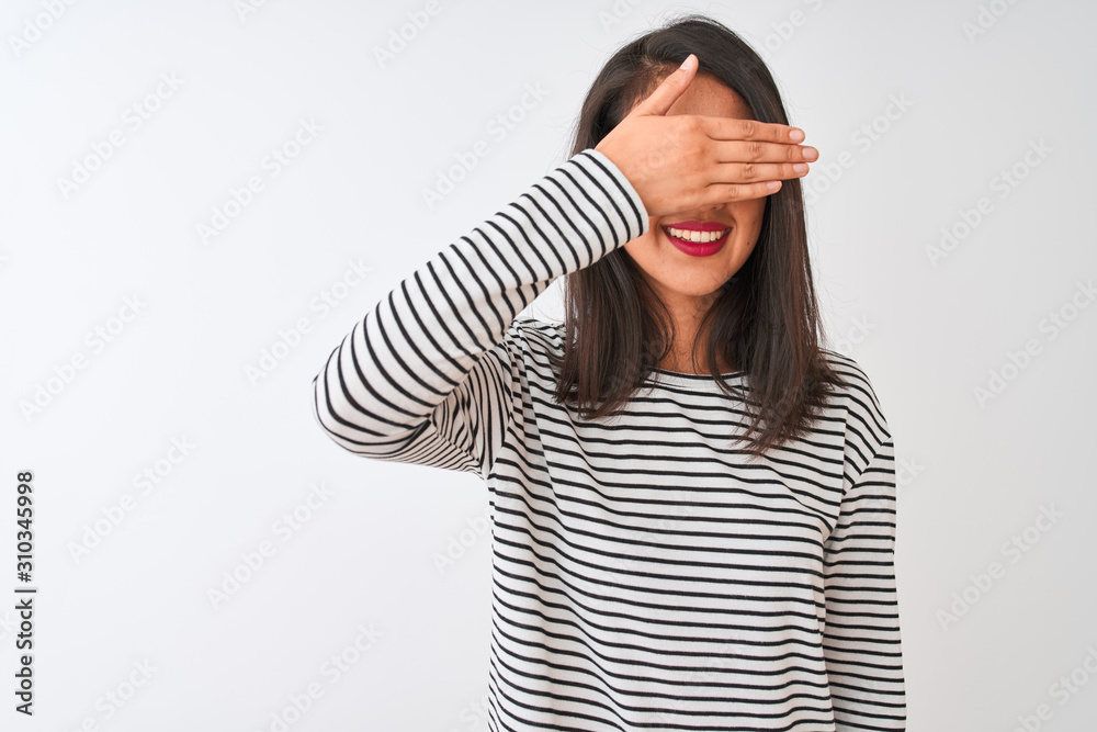 Chinese woman wearing striped t-shirt and sunglasses standing over isolated white background smiling and laughing with hand on face covering eyes for surprise. Blind concept. Chinese woman wearing striped t-shirt and sunglasses standing over isolated white background smiling and laughing with hand on face covering eyes for surprise. Blind concept.