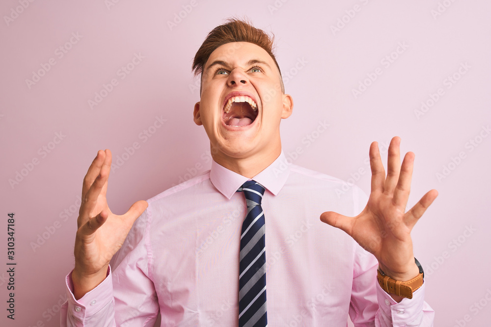 Young handsome businessman wearing shirt and tie standing over isolated pink background crazy and mad shouting and yelling with aggressive expression and arms raised. Frustration concept. Young handsome businessman wearing shirt and tie standing over isolated pink background crazy and mad shouting and yelling with aggressive expression and arms raised. Frustration concept.