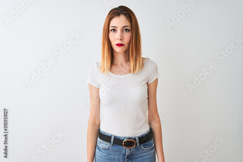 Beautiful redhead woman wearing casual t-shirt standing over isolated white background Relaxed with serious expression on face. Simple and natural looking at the camera.