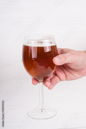 male hand holding a glass of homemade craft beer on white background.  Ale or lager from pilsner malt