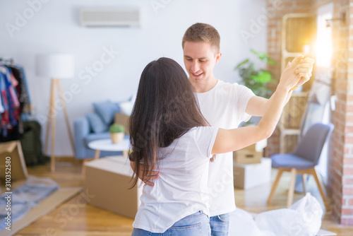 Young beautiful couple dancing at new home around cardboard boxes