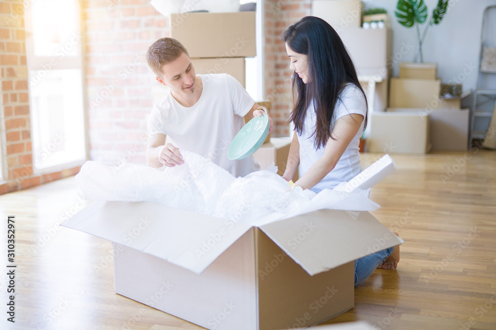 Obraz premium Young beautiful couple open cardboard boxes to order new home