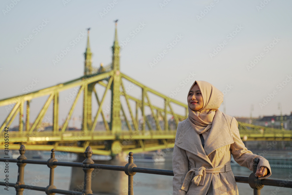 a stylish young lady with a bridge, sea and blue sky as her background