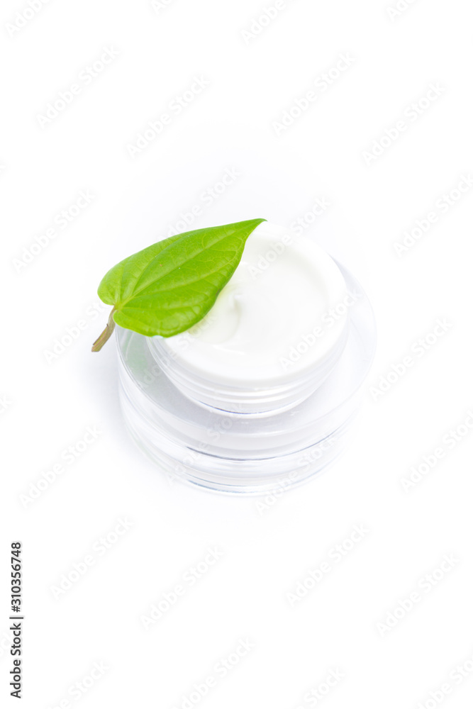 Cosmetic bottle container with green leaves, isolated on white background.