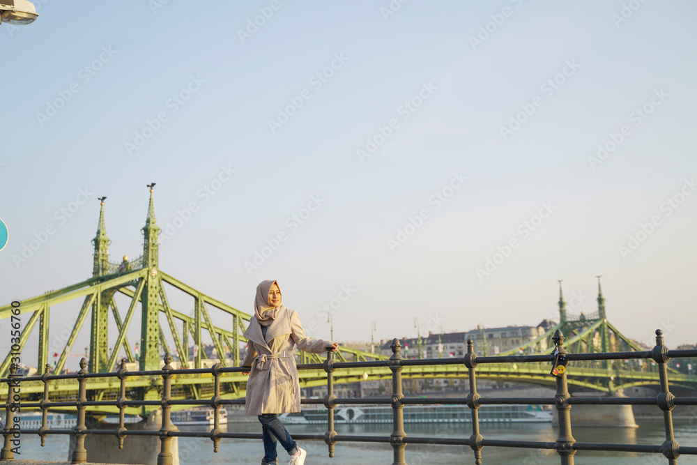 a stylish young lady with a bridge, sea and blue sky as her background