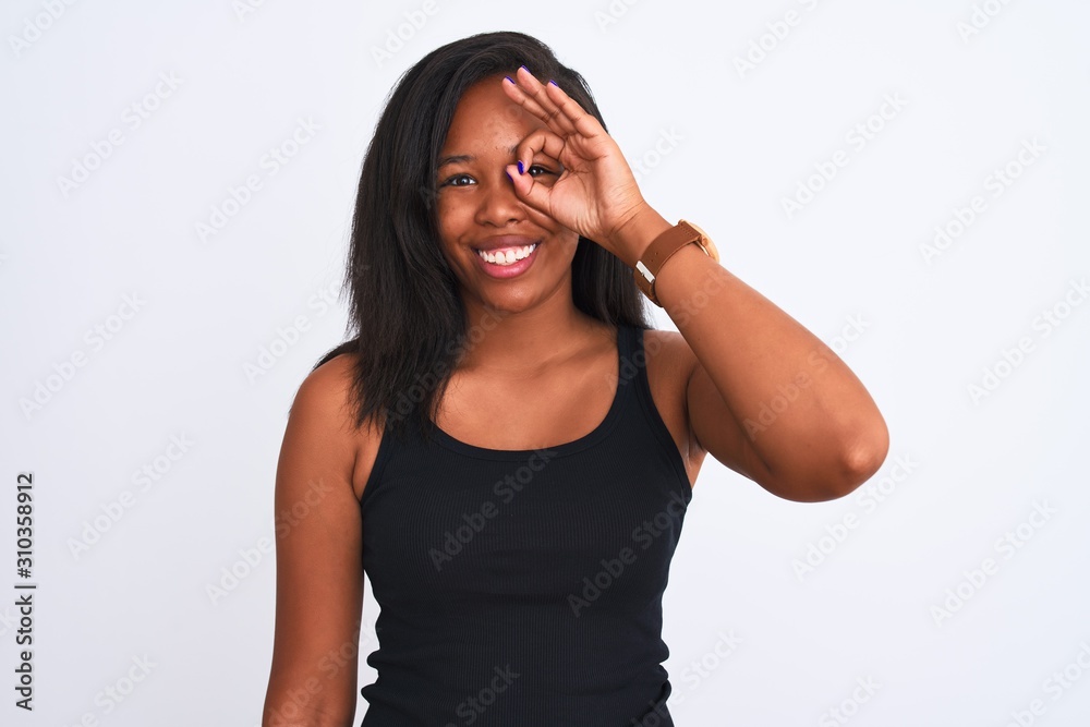 Beautiful young african american woman over isolated background doing ok gesture with hand smiling, eye looking through fingers with happy face. Beautiful young african american woman over isolated background doing ok gesture with hand smiling, eye looking through fingers with happy face.