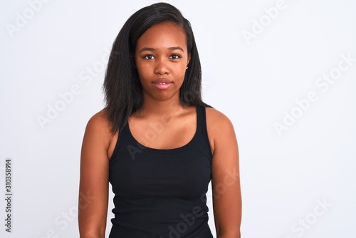Beautiful young african american woman over isolated background with serious expression on face. Simple and natural looking at the camera. © Krakenimages.com