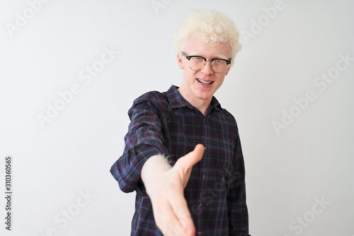 Young albino blond man wearing casual shirt and glasses over isolated white background smiling friendly offering handshake as greeting and welcoming. Successful business.
