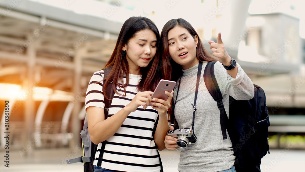 Fototapeta premium Two Teenager travellers checking location map on smartphone