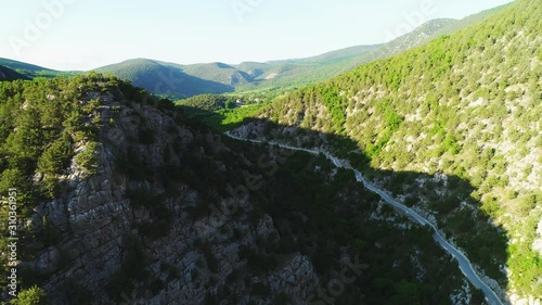 Aerial view of road going through a green mountains covered with shrubs and grass against blue sky in subber day. Shot. Beautiful view from above photo