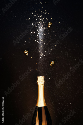 Festive Christmas background. Bottle of champagne with a spray of sparkles and Christmas decorations. Happy new year concept