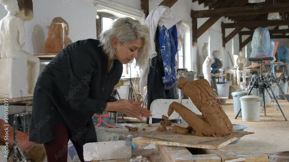 Sculptress Sculptor is sculpting realistic, figurative model in large studio Sculptress Sculptor is sculpting realistic, figurative model in large studio