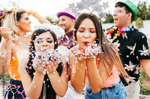 Brazilian Carnival. Young women in costume enjoying the carnival party blowing confetti