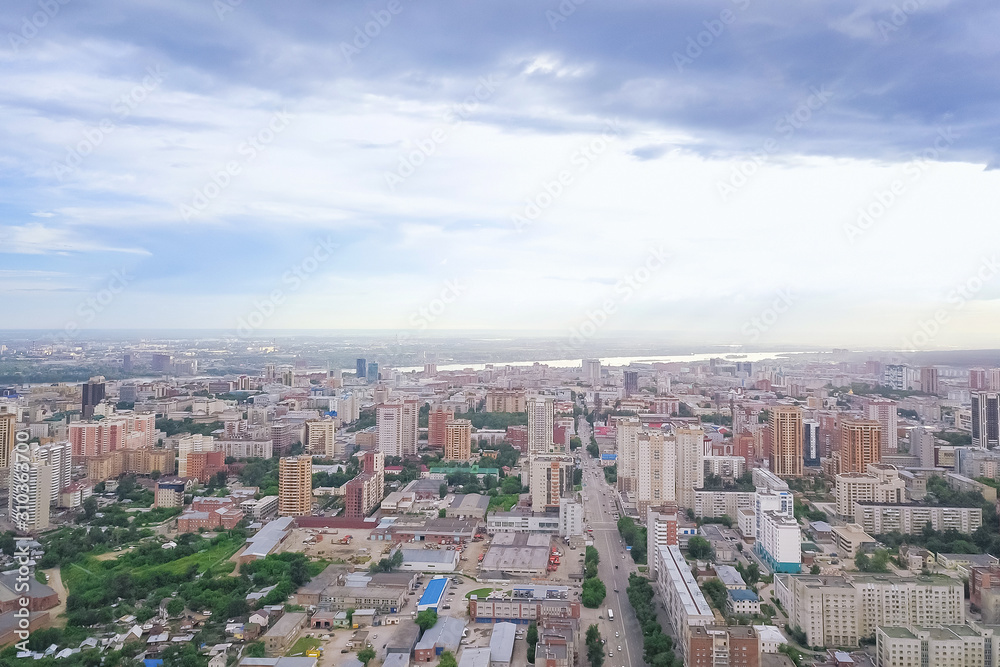 Aerial view of the landscape in a big city with high houses and skyscrapers in the center of Novosibirsk under a beautiful blue sky with clouds on a summer cloudy day.