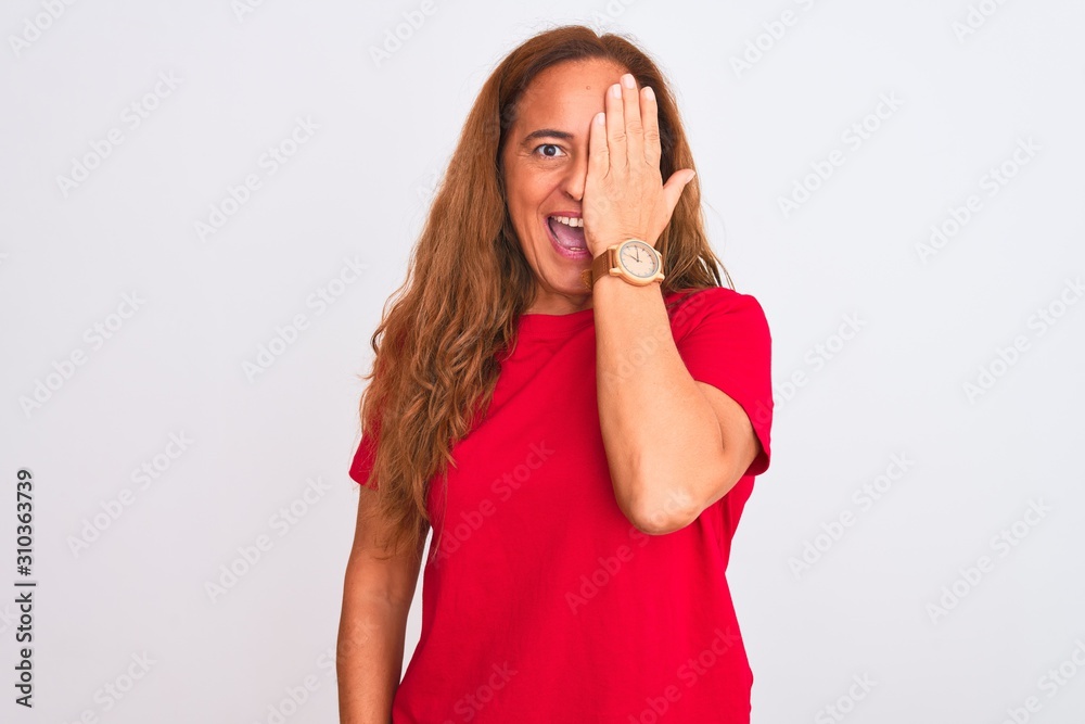 Middle age mature woman standing over white isolated background covering one eye with hand, confident smile on face and surprise emotion. Middle age mature woman standing over white isolated background covering one eye with hand, confident smile on face and surprise emotion.