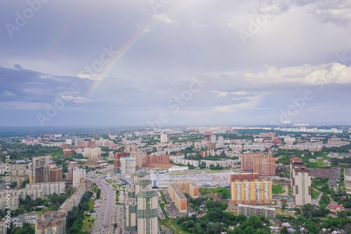 Aerial view of the landscape in a big city with high houses and skyscrapers in the center of Novosibirsk under a beautiful blue sky with clouds on a summer cloudy day with rainbow.
