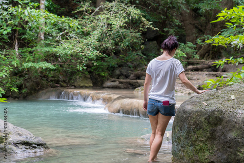 young cute hipster girl travelling at beautiful Erawan waterfall mountains green forest hiking views at Kanchanaburi, Thailand. guiding idea for female backpacker woman women backpacking