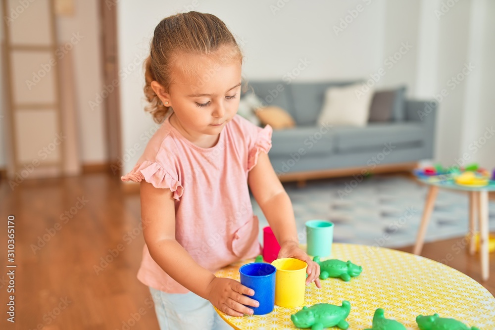 Beautiful blond toddler girl playing with plastic frogs toys at kindergarten Beautiful blond toddler girl playing with plastic frogs toys at kindergarten