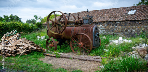 Photography Rusty antique farm equipment next to stone building