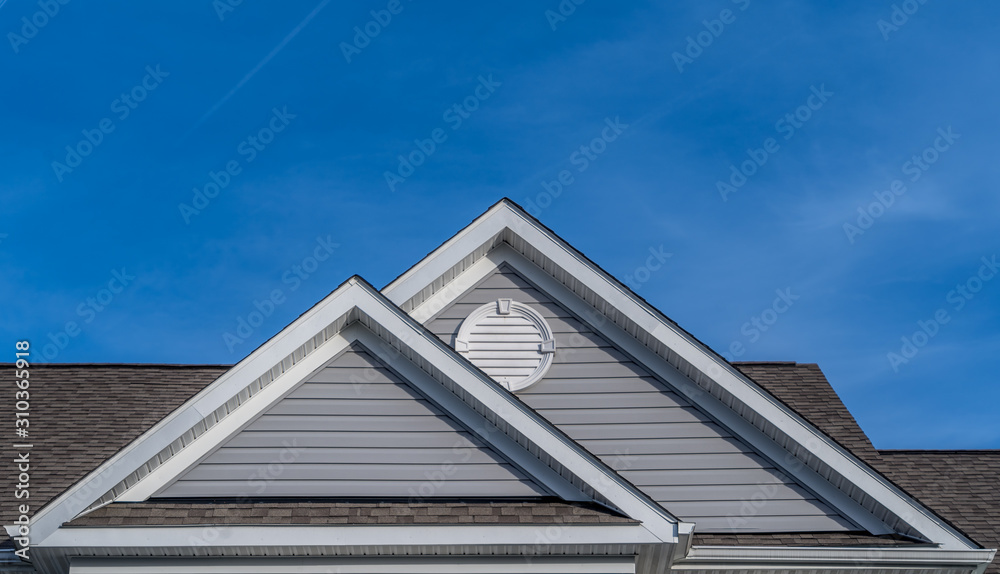 Reverse double gable close up on luxury single family residential home. White round louver vent. . Roof line of traditional home with one gable running one way reverse gables running the other. Reverse double gable close up on luxury single family residential home. White round louver vent. . Roof line of traditional home with one gable running one way reverse gables running the other.