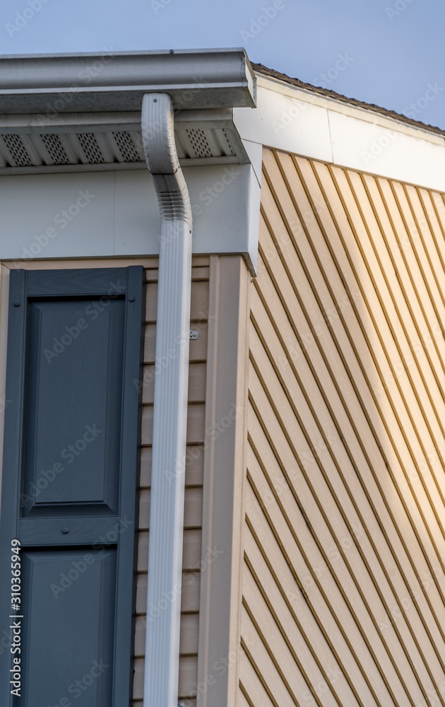 Horizontal vinyl siding, white frame gutter guard system, fascia, drip edge, soffit, on a pitched roof attic at a luxury American single family home neighborhood USA