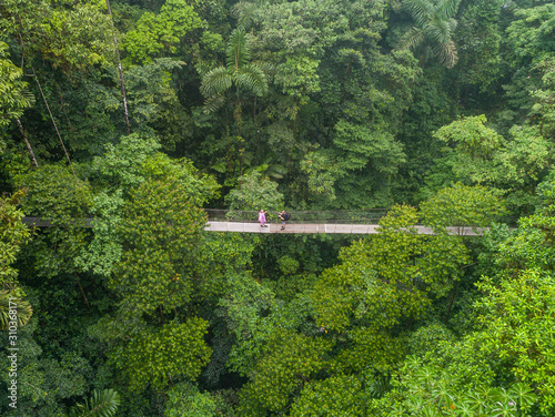 Couple walking over mystico hanging bridges at La Fortuna rainforest aerial drone view in Costa Rica jungle