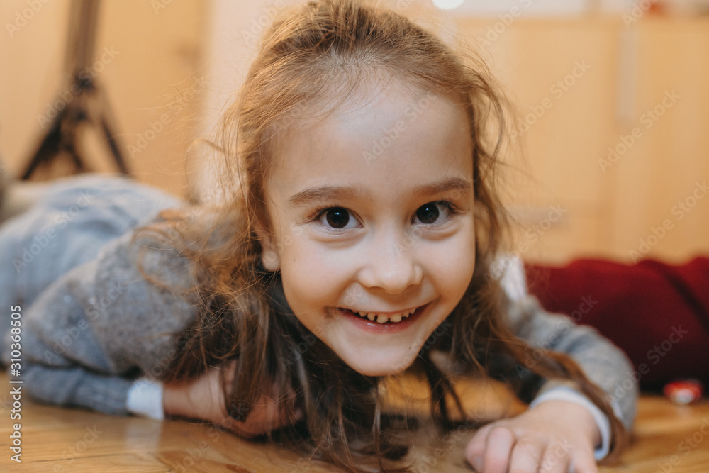 Close up portrait of a lovely little girl looking at camera smiling while playing at home leanin on the floor . Close up portrait of a lovely little girl looking at camera smiling while playing at home leanin on the floor .