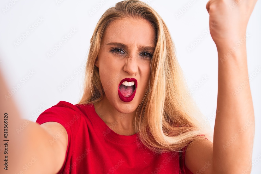 Young beautiful woman wearing t-shirt make selfie by camera over isolated white background annoyed and frustrated shouting with anger, crazy and yelling with raised hand, anger concept Young beautiful woman wearing t-shirt make selfie by camera over isolated white background annoyed and frustrated shouting with anger, crazy and yelling with raised hand, anger concept