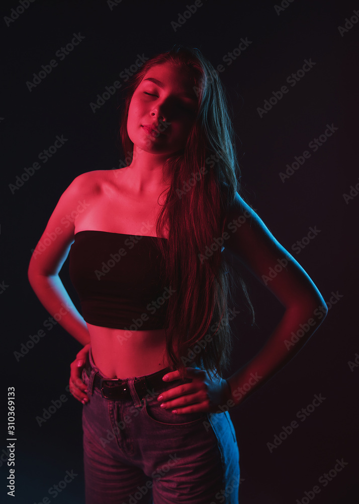 Slim, beautiful young girl in black top posing in neon red and blue light  Stock Photo | Adobe Stock