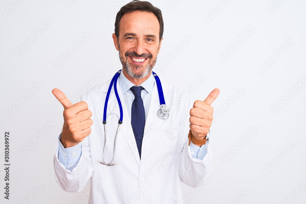 Middle age doctor man wearing coat and stethoscope standing over isolated white background success sign doing positive gesture with hand, thumbs up smiling and happy. Cheerful expression and winner Middle age doctor man wearing coat and stethoscope standing over isolated white background success sign doing positive gesture with hand, thumbs up smiling and happy. Cheerful expression and winner