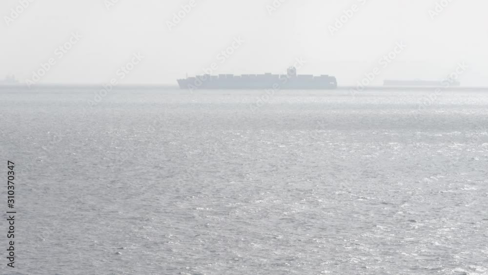 Silhouette of large container ship in horizon of sea in fog Silhouette of large container ship in horizon of sea in fog