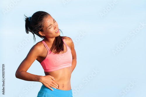 Side stitch - woman runner side cramps after running. Jogging woman with stomach side pain after jogging work out. Female athlete. photo