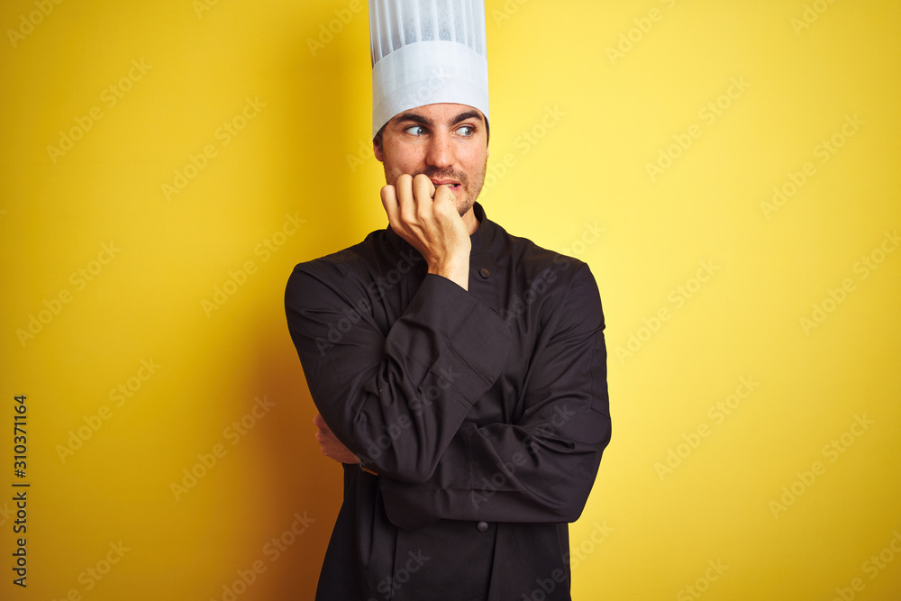 Young chef man wearing uniform and hat standing over isolated yellow background looking stressed and nervous with hands on mouth biting nails. Anxiety problem. Young chef man wearing uniform and hat standing over isolated yellow background looking stressed and nervous with hands on mouth biting nails. Anxiety problem.