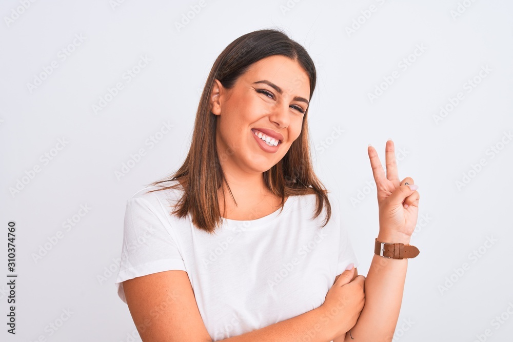 Portrait of beautiful and young brunette woman standing over isolated white background smiling with happy face winking at the camera doing victory sign. Number two. Portrait of beautiful and young brunette woman standing over isolated white background smiling with happy face winking at the camera doing victory sign. Number two.