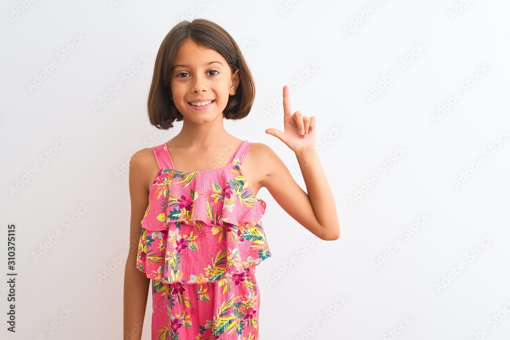 Young beautiful child girl wearing pink floral dress standing over isolated white background showing and pointing up with fingers number two while smiling confident and happy. Young beautiful child girl wearing pink floral dress standing over isolated white background showing and pointing up with fingers number two while smiling confident and happy.