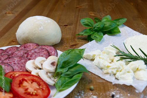Dough basis and ingredients for pizza, on the wood table