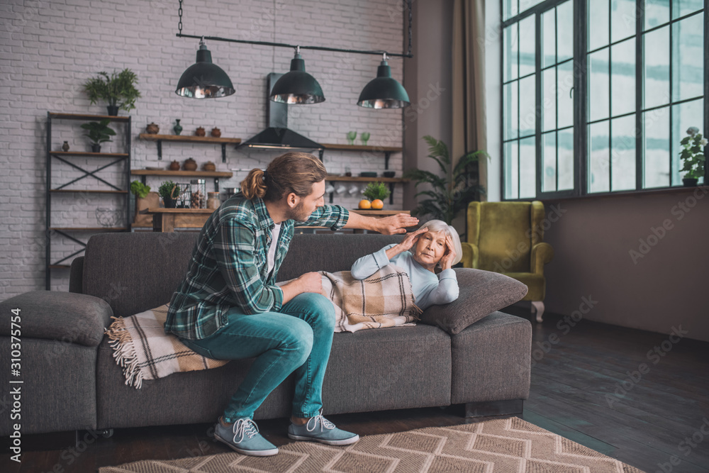 Naklejka premium Young man in jeans taking care of his sick mom