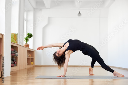 Fit sporty flexible girl doing backbend stretching exercise. Camatkarasana Wild Thing or Flip-the-Dog pose. Black and white view. Copy space on top on white background. Grace, beauty, strength, health