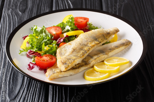 Obraz na plátne Healthy fried pikeperch fillet with salad and lemon closeup in a plate