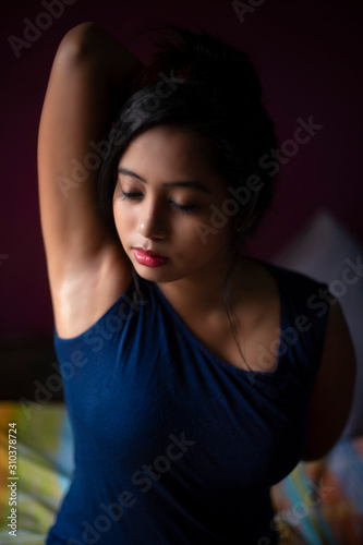 An young and attractive Indian Bengali brunette woman in active wear is doing exercise and yoga after waking up in the morning in front of window in her room. Indian lifestyle.