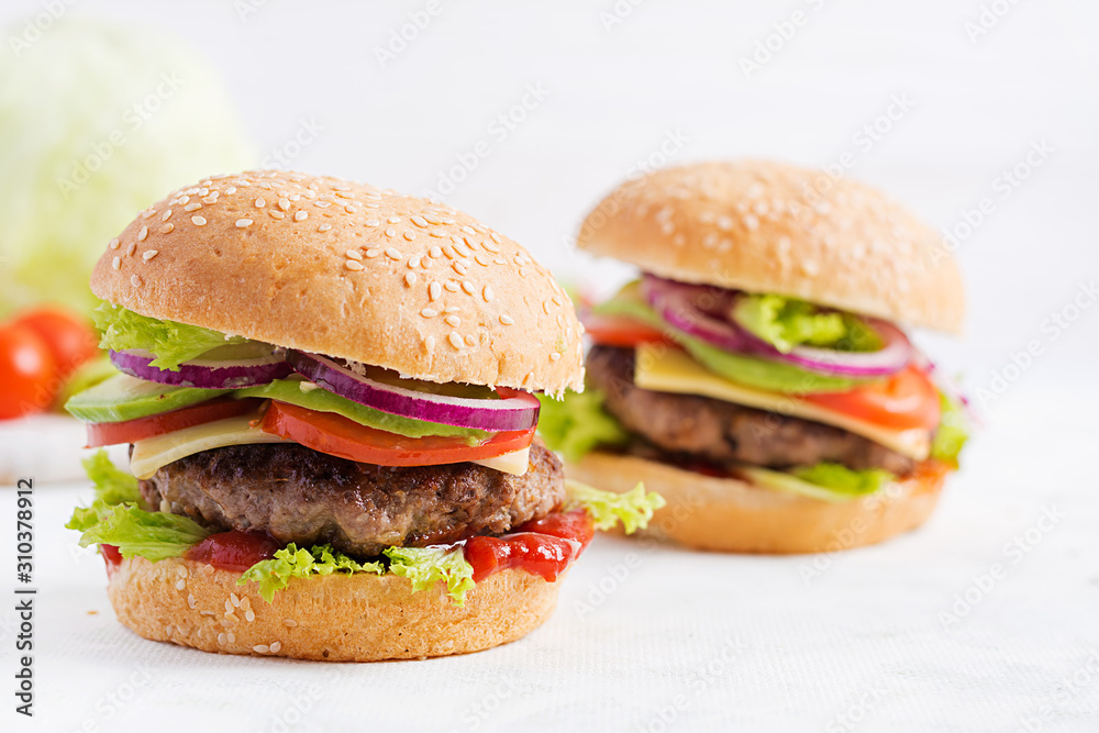 Big sandwich - hamburger burger with beef, avocado, tomato and red onions on light background. American cuisine. Fast Food Big sandwich - hamburger burger with beef, avocado, tomato and red onions on light background. American cuisine. Fast Food