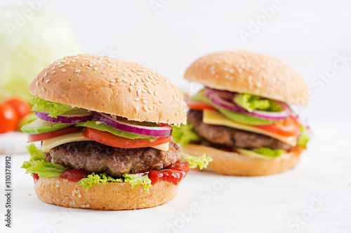 Big sandwich - hamburger burger with beef, avocado, tomato and red onions on light background. American cuisine. Fast Food