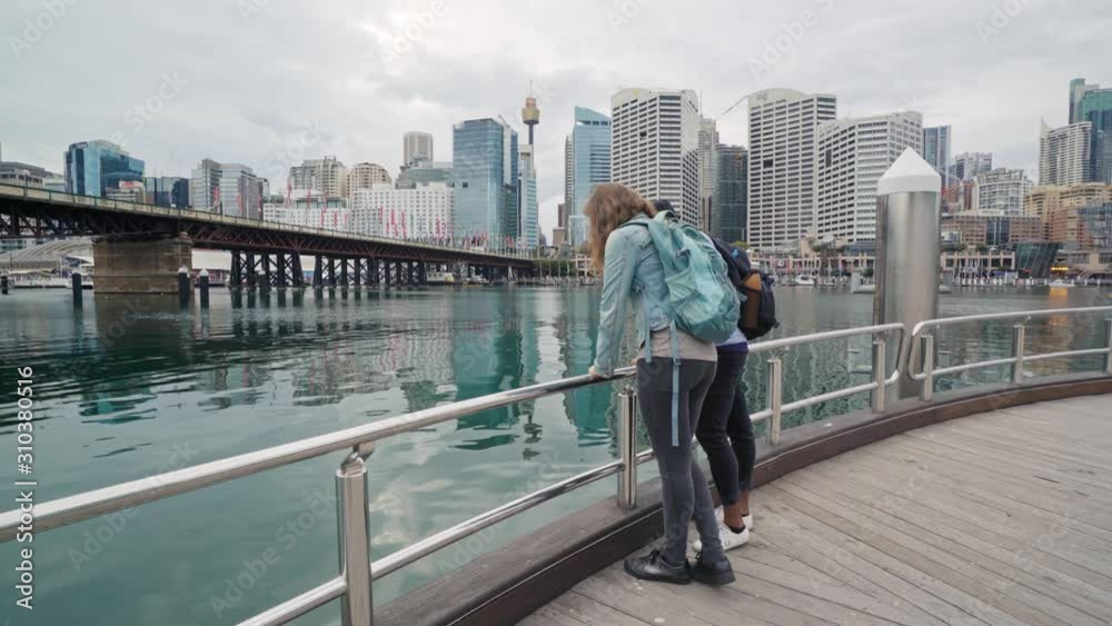 Trendy multiracial couple leaning on the rail at a harbor looking at something in the water Trendy multiracial couple leaning on the rail at a harbor looking at something in the water