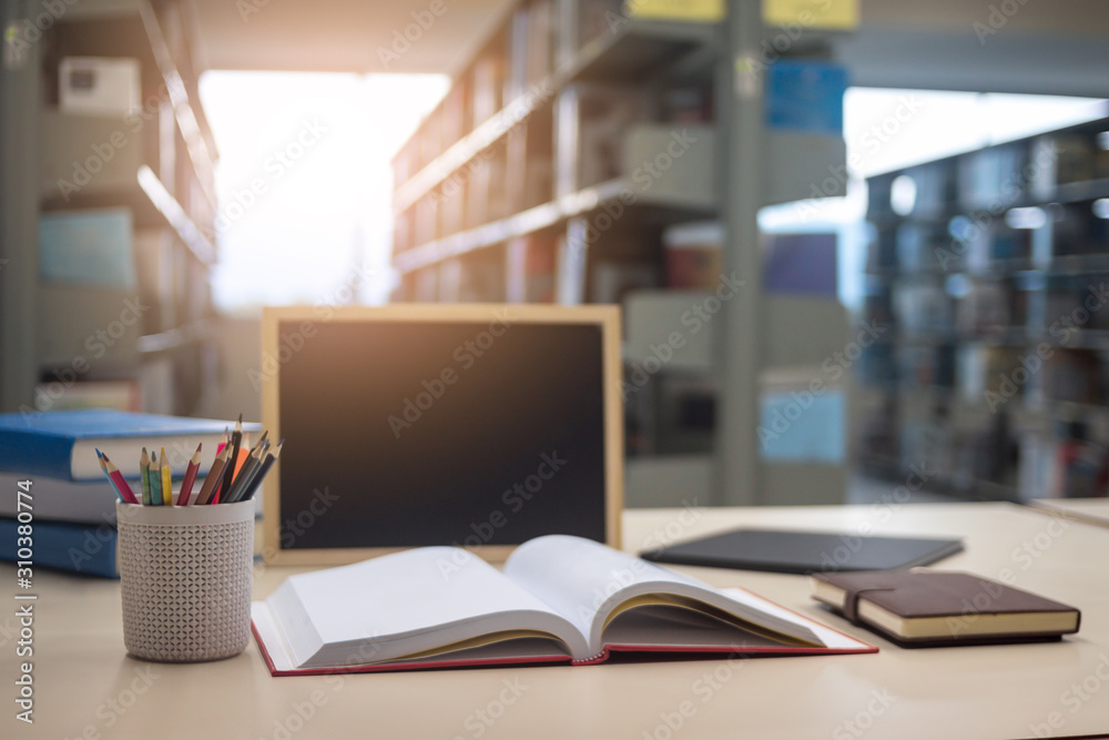 Education Concept, book, blackboard, pencil and notebook on table in library.
