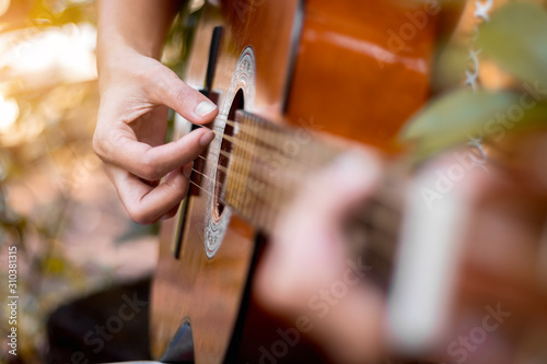 Close up hand of woman playing acoustic guitar.
