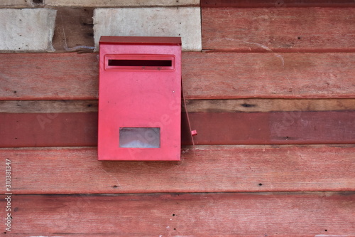 red mailbox on wooden wall